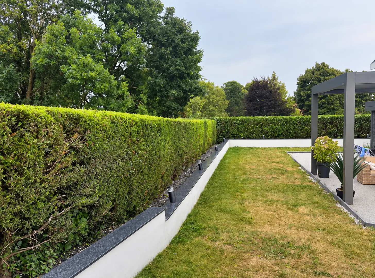 Jardin paysager entretenu avec haie alignée et pelouse tondue