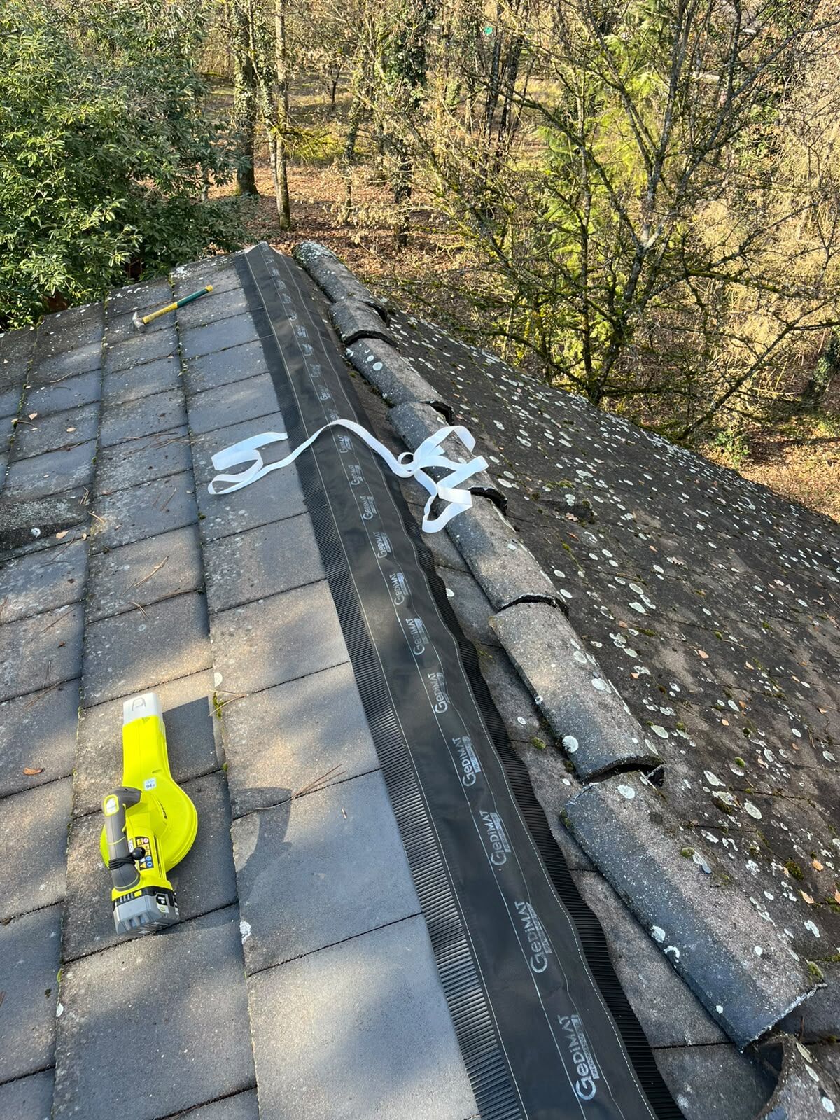 Closoir de faîtage neuf posé sur un toit en tuiles béton avant repose des faîtières